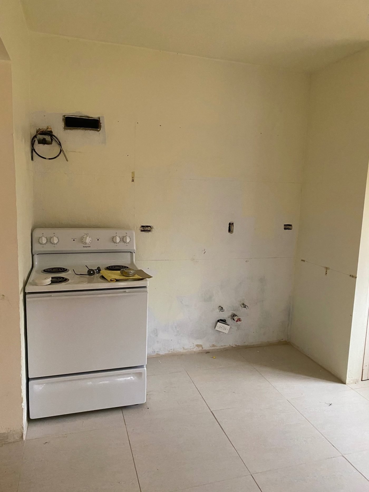 Dated condominium kitchen before renovation, with a wall closing off the room
