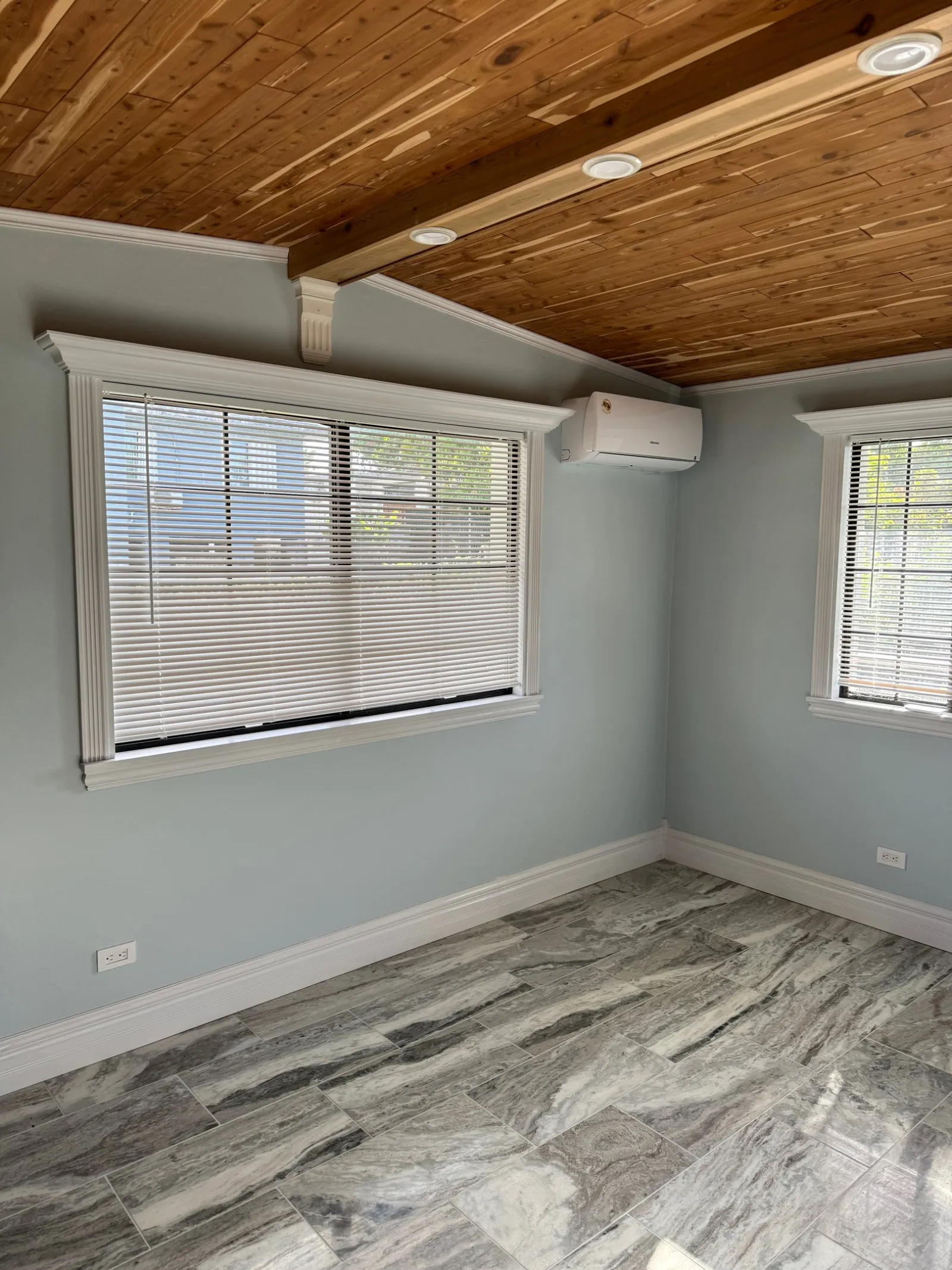 Bedroom finished with a cedar plank ceiling and marble-look tile floor.