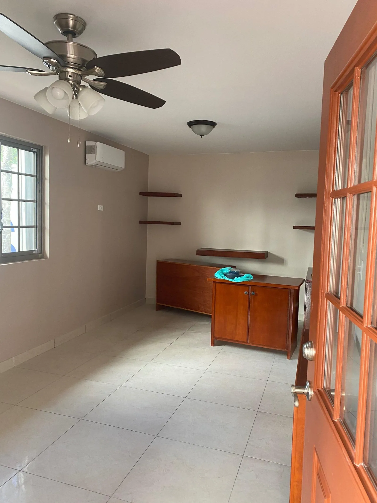 The same room rebuilt: painted walls, large-format tile, a ceiling fan and a split unit