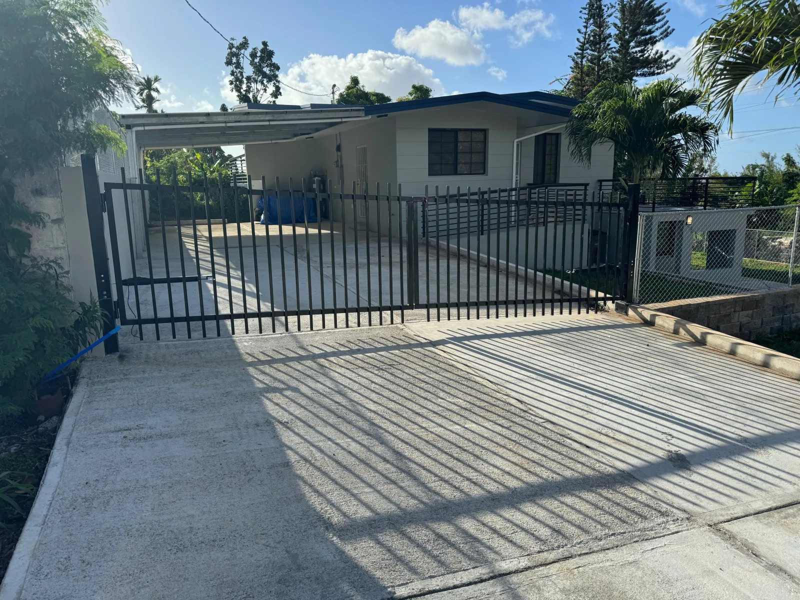 Steel picket gate and slat fencing over a new broom-finished driveway.