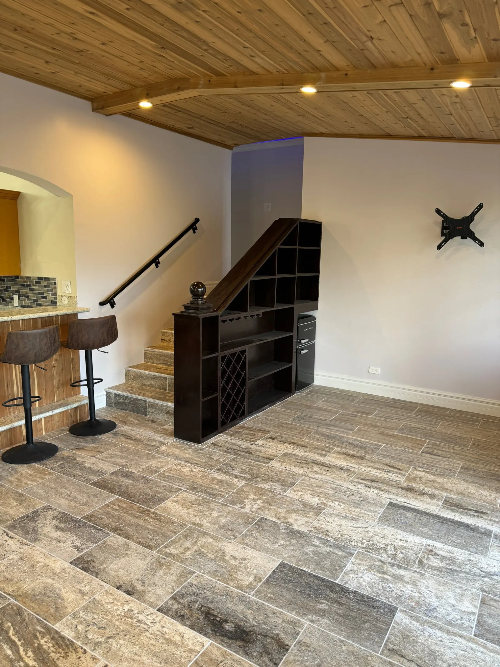Living room with a cedar plank ceiling and a wine rack built in under the stair.